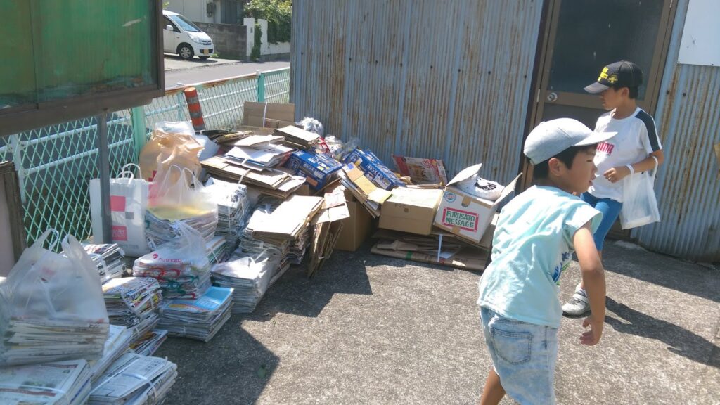 廃品回収で集めたごみを集積所にまとめている子どもの写真